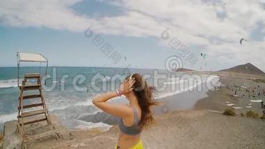 风天，年轻迷人的女人站在海边。 在后台放风筝的地方